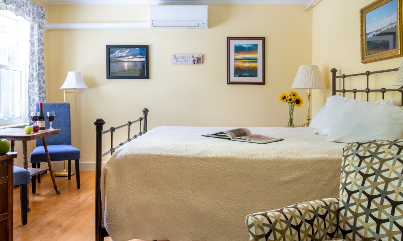 Bedroom showing the queen bed, parsons chairs, flat screen TV and dresser.