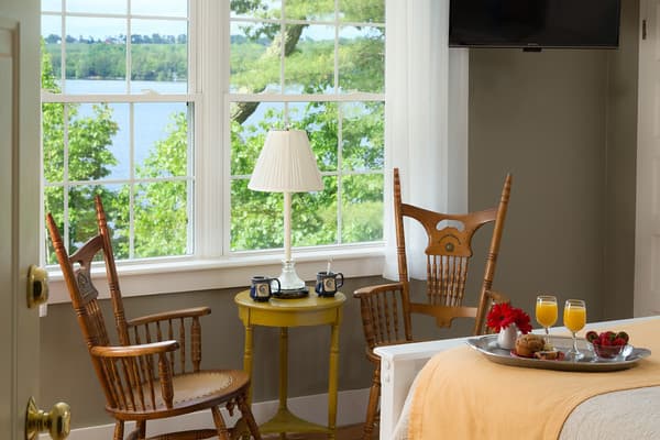 The two antique wooden chairs and a small table set by the large window overlooking Tripp Lake.