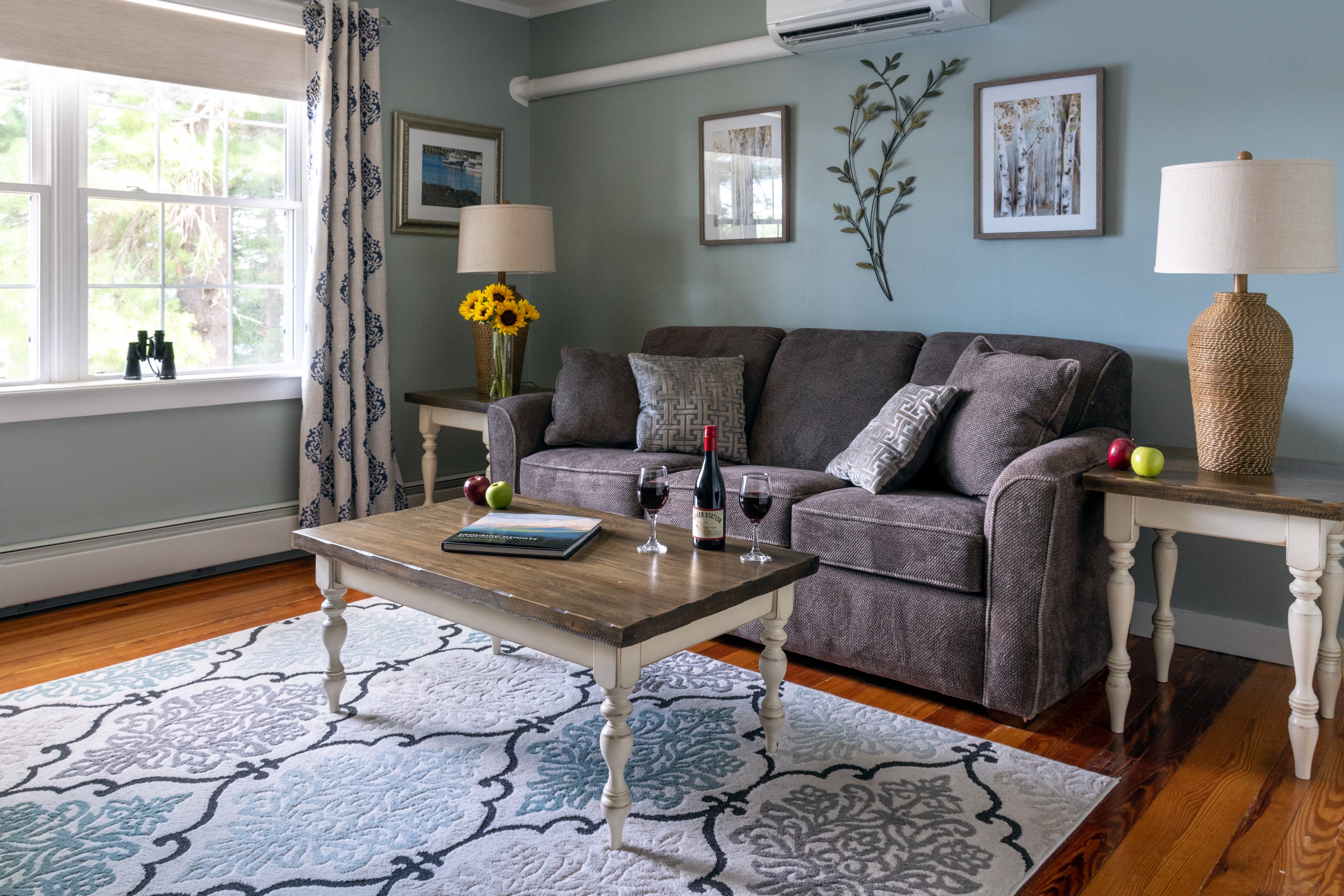 The sitting room with sofa, recliner, flat screen TV, coffee table and large window overlooking the lake.