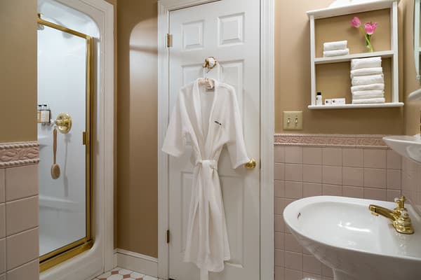 Bathroom with shower stall, pedestal sink and robe provided for guest use.