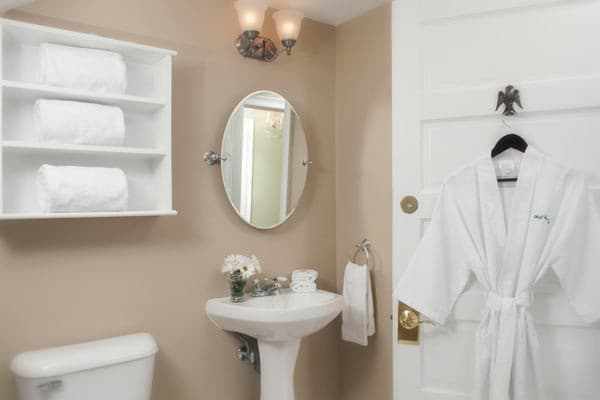 Bathroom view of the pedestal sink, mirror and robe for guest use.
