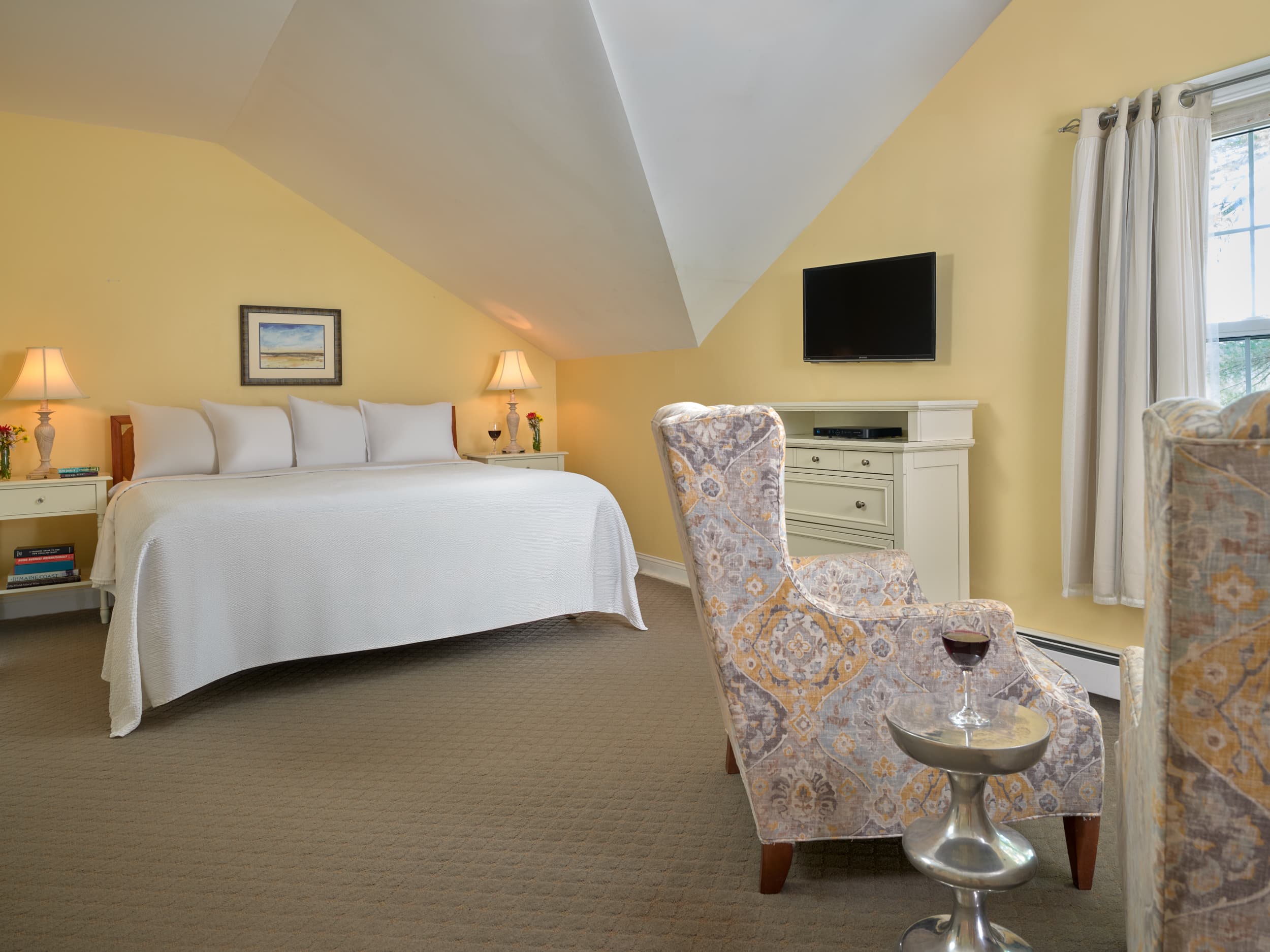 The king bed, dresser, Roku 4k TV, and two wing chairs facing the window overlooking the lake.