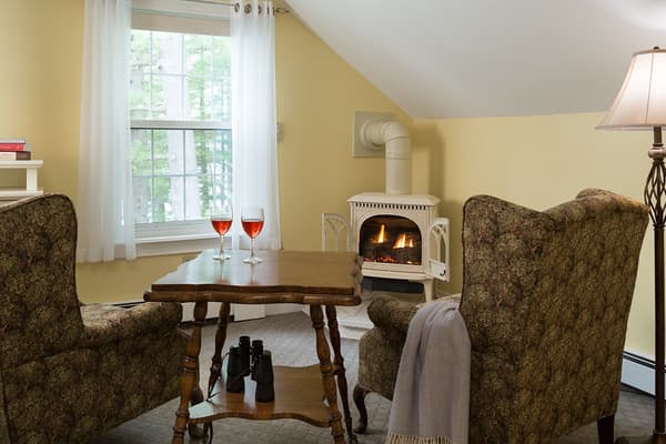 Two wing chairs and a table facing the window and corner propane fireplace.