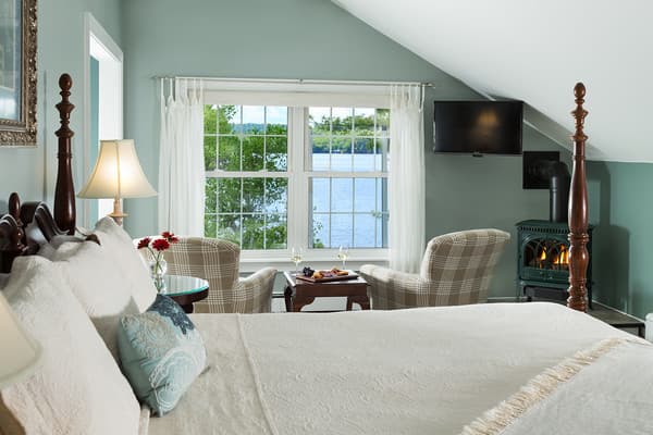 The 4 poster king bed, two chairs facing a large window overlooking the lake and a small propane corner fireplace.