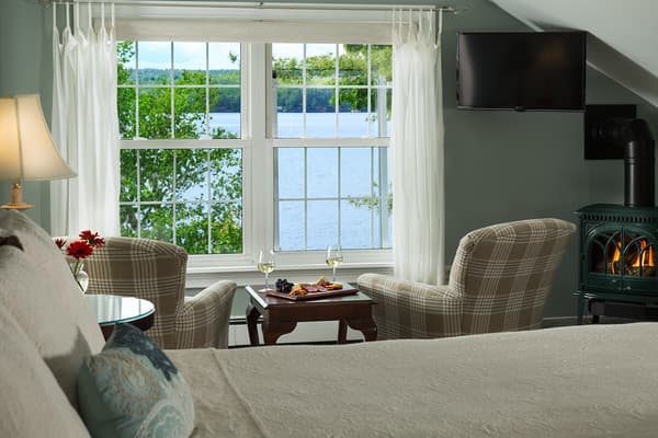 Closeup view of the king bed, chairs overlooking the lake, flat screen TV and fireplace.