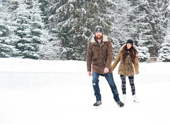 A couple ice skating in a snowy landscape.