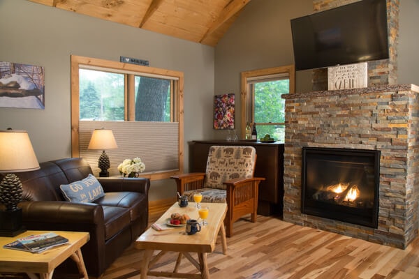 Cabin seating area with leather loveseat, chair and coffee table overlooking the stone fireplace and flat screen TV.