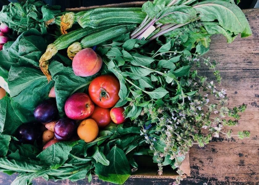 A variety of fresh vegetables, fruits, and herbs arranged in a wooden crate. A variety of fresh vegetables, fruits, and herbs arranged in a wooden crate.