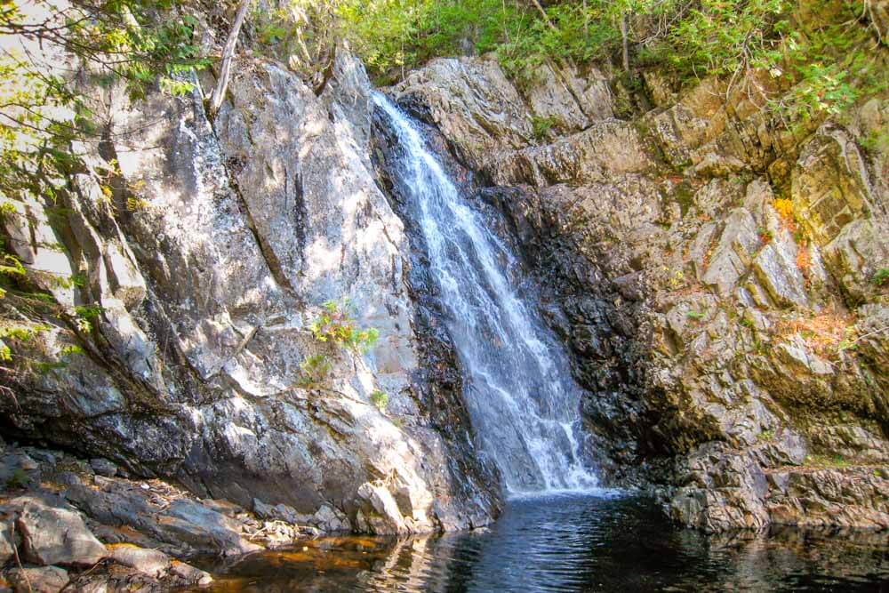 A cascading waterfall flows over rocky terrain into a serene pool below.