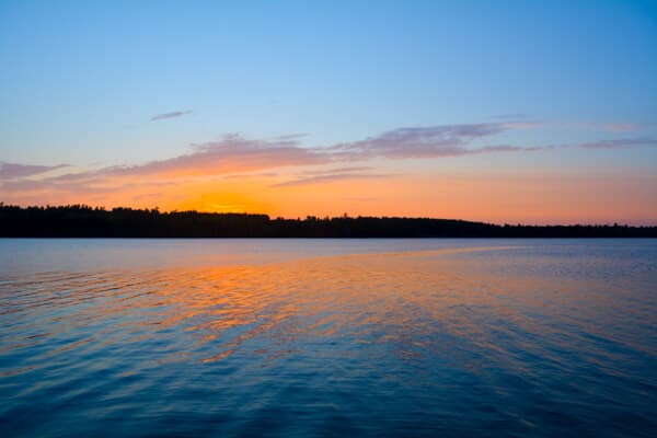 A tranquil lake at sunset reflecting vibrant orange and blue hues.