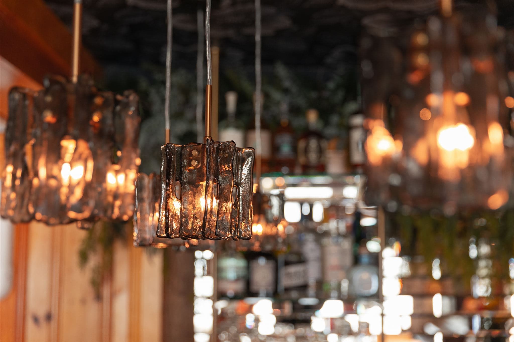 A close-up of artistic pendant lights illuminating a bar area.