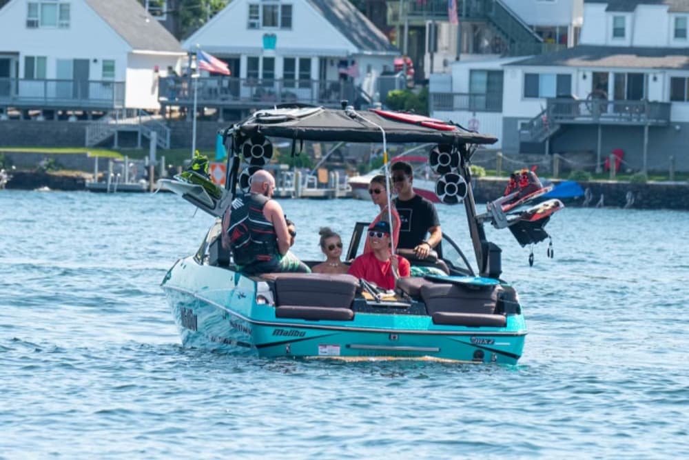 A group of people enjoys a day on a turquoise boat on a sunny lake.