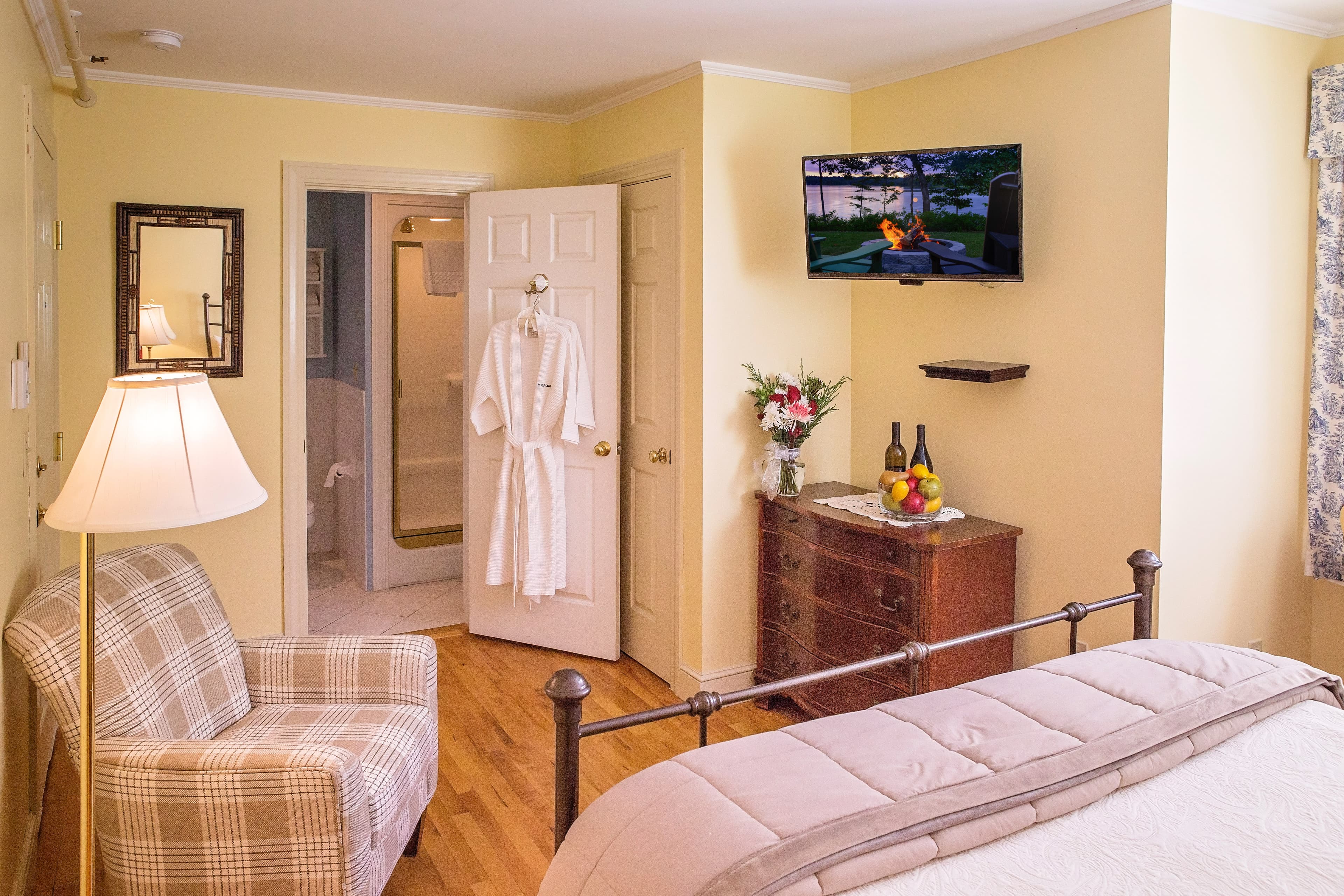 View of the bathroom as seen from the bedroom including flat screen TV and dresser.