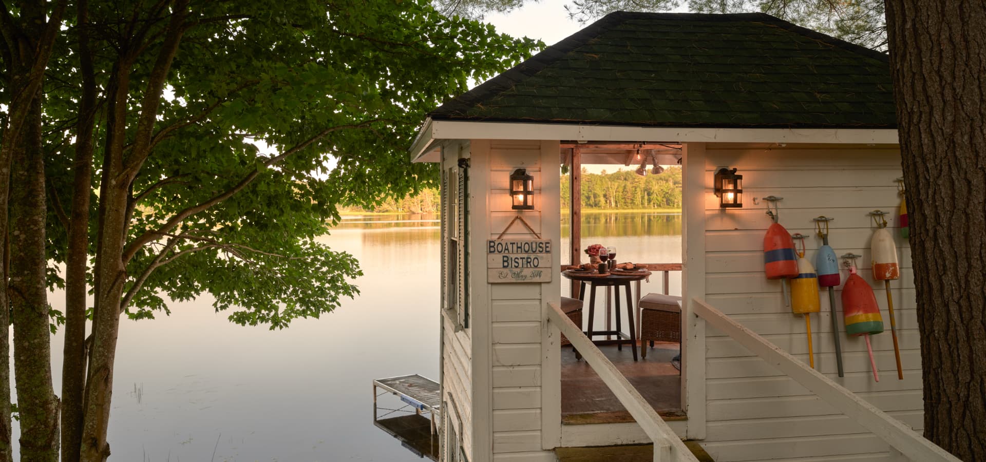 A charming boathouse bistro with a picturesque lakeside view, featuring rustic decor and outdoor seating.