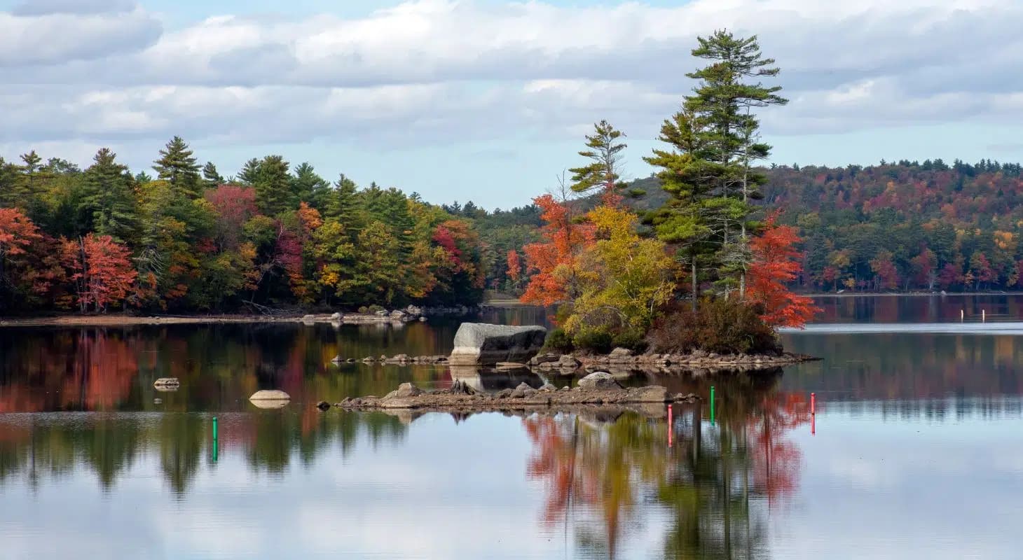 A tranquil lake scene with colorful autumn trees reflecting on the water.