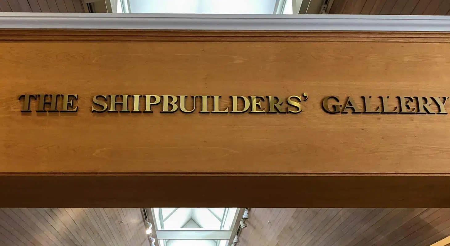 Sign for "The Shipbuilders' Gallery" in gold lettering on wooden background.