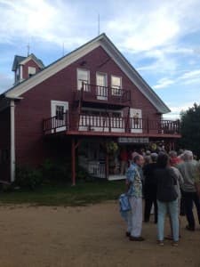 A crowd gathers in front of a red building with balconies under a blue sky.