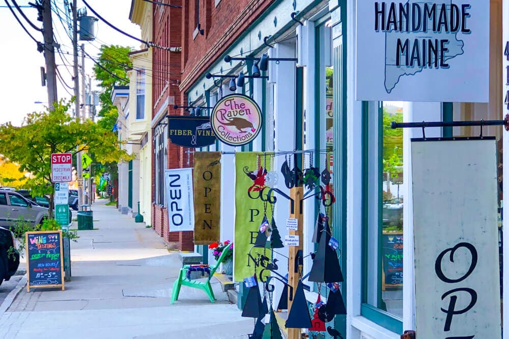 A colorful street lined with shops displaying handmade signs and storefronts.