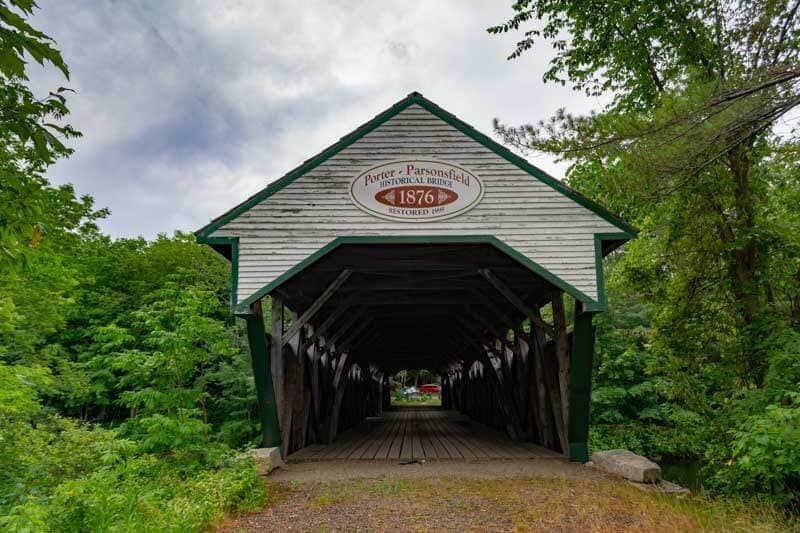 A historic covered bridge surrounded by lush greenery, dated 1876.