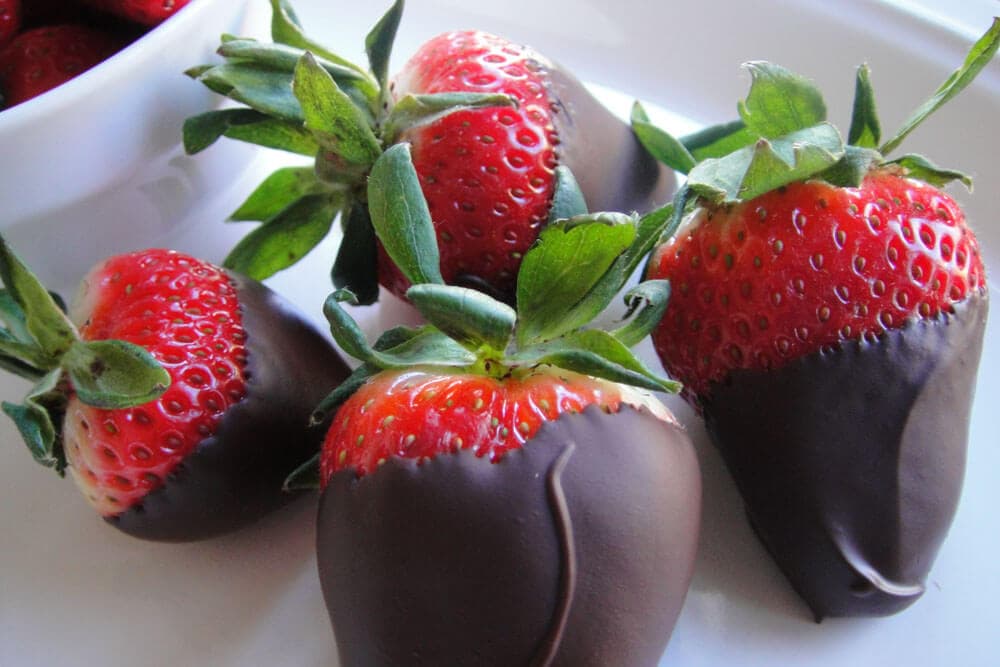 Chocolate-dipped strawberries arranged on a white plate.
