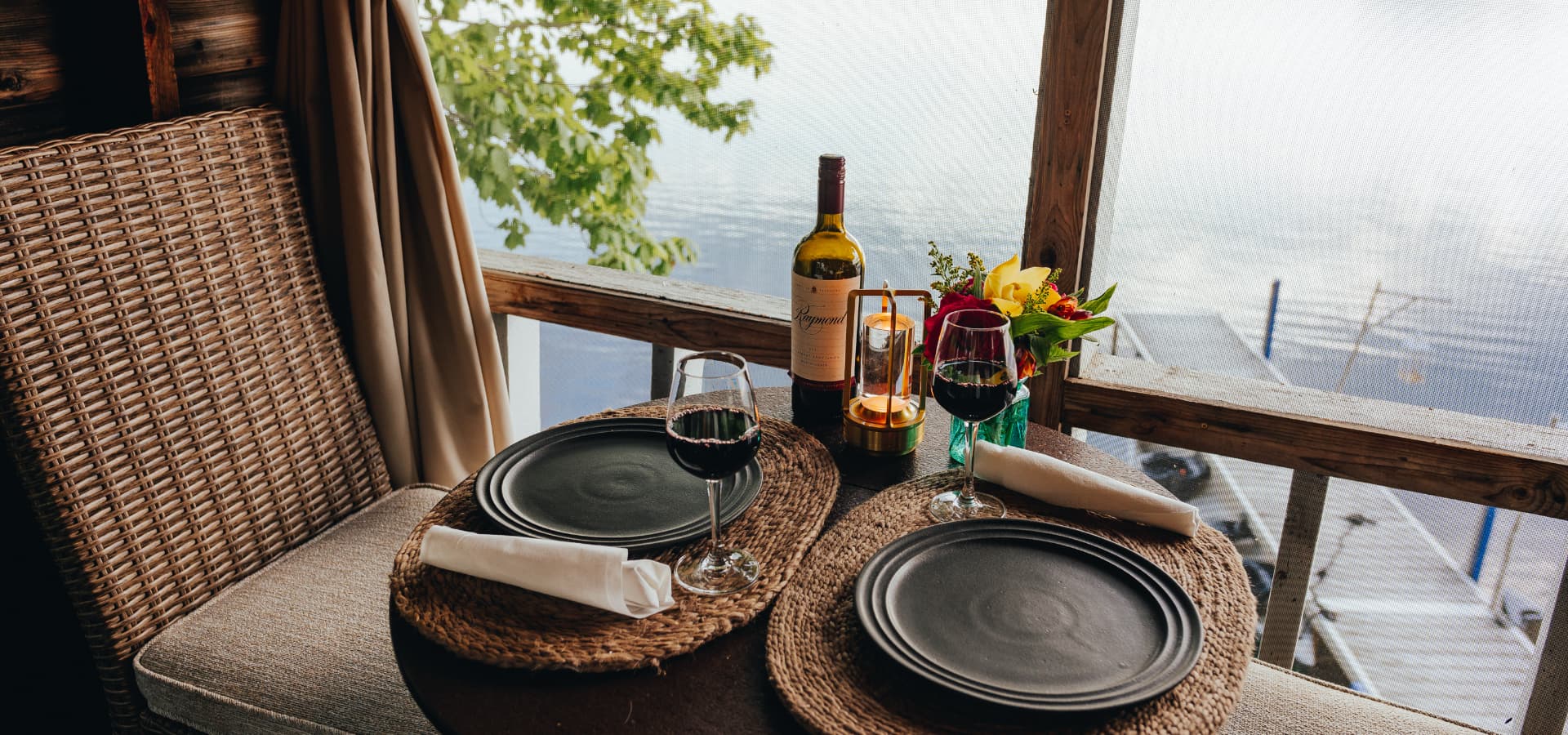 A cozy dining setup with wine and flowers overlooking a serene lake.