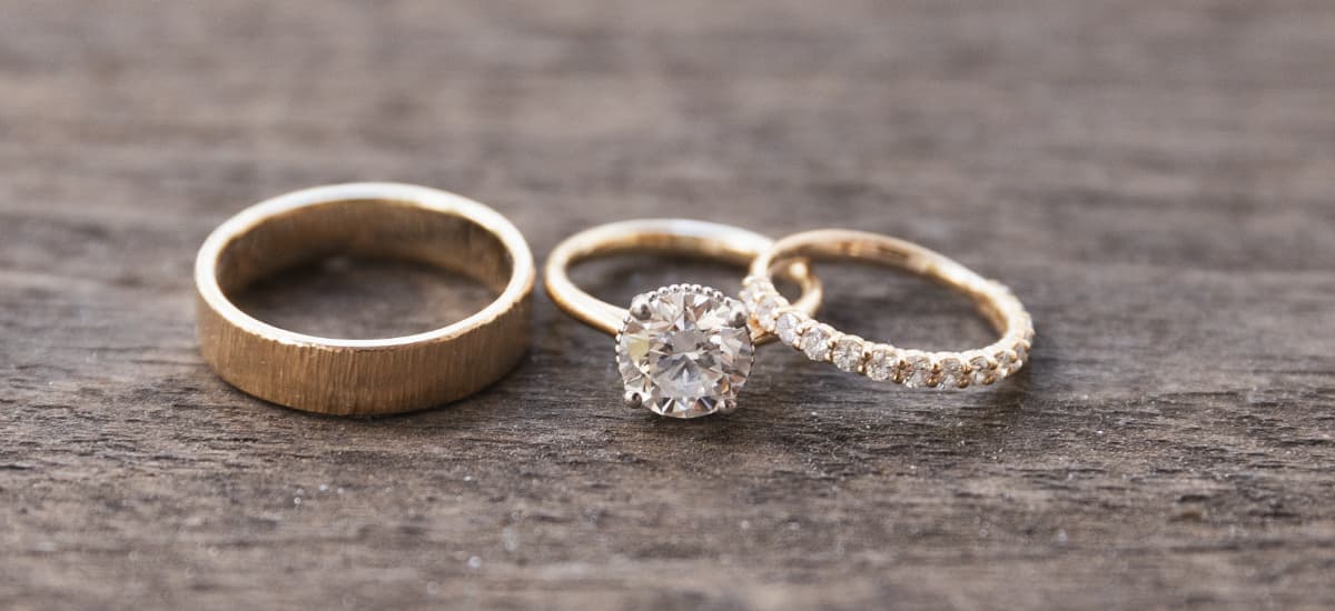 Three elegant gold rings arranged on a wooden surface.