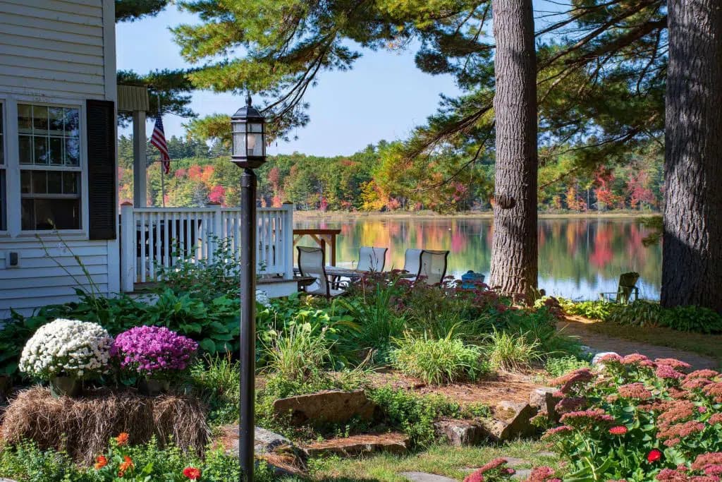 A serene lakeside garden with colorful flowers and a cozy seating area.