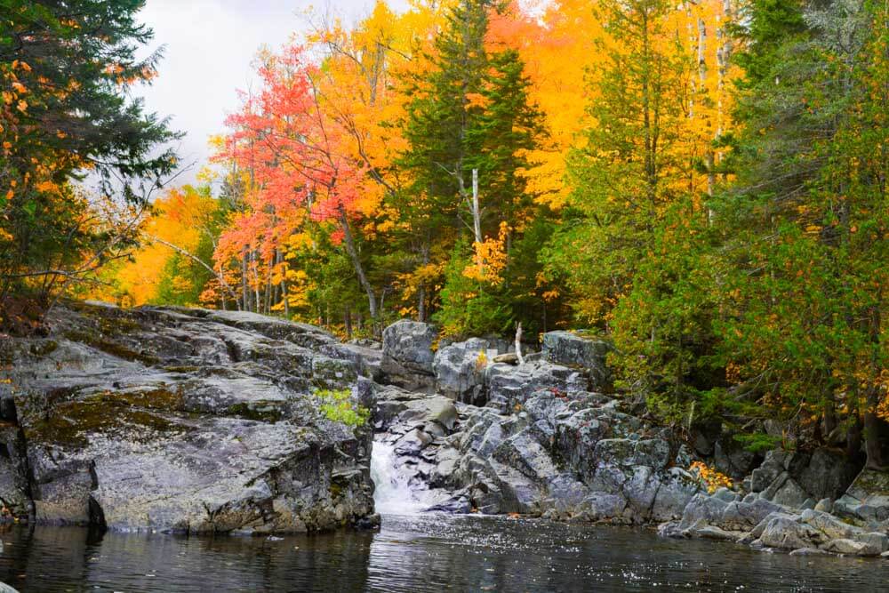 A serene river scene surrounded by vibrant autumn foliage and rocky terrain.