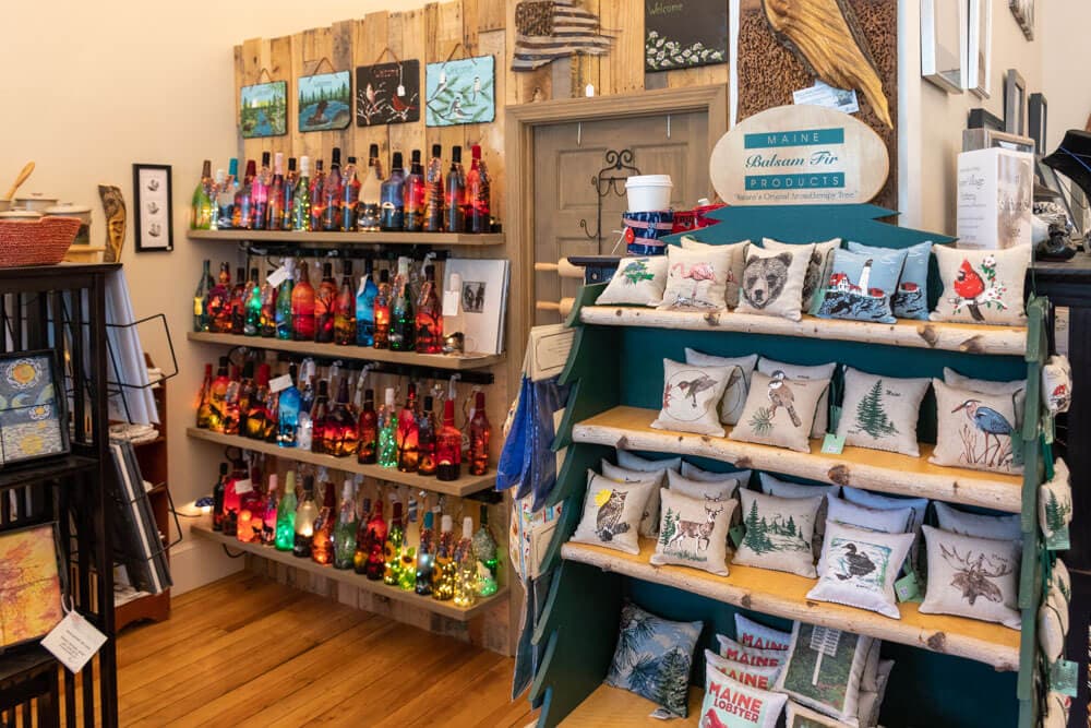 A colorful display of decorative bottles and embroidered pillows in a cozy shop.