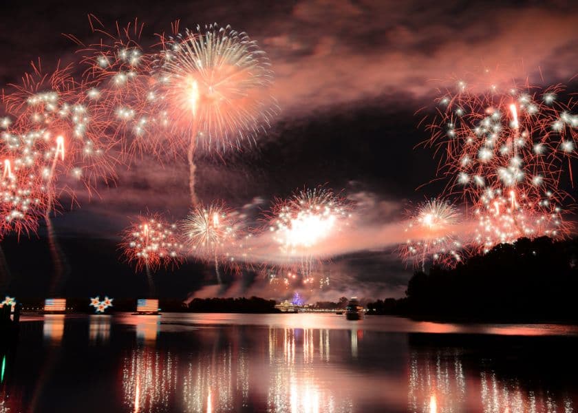 Colorful fireworks illuminate the night sky above a calm body of water. Colorful fireworks illuminate the night sky above a calm body of water.