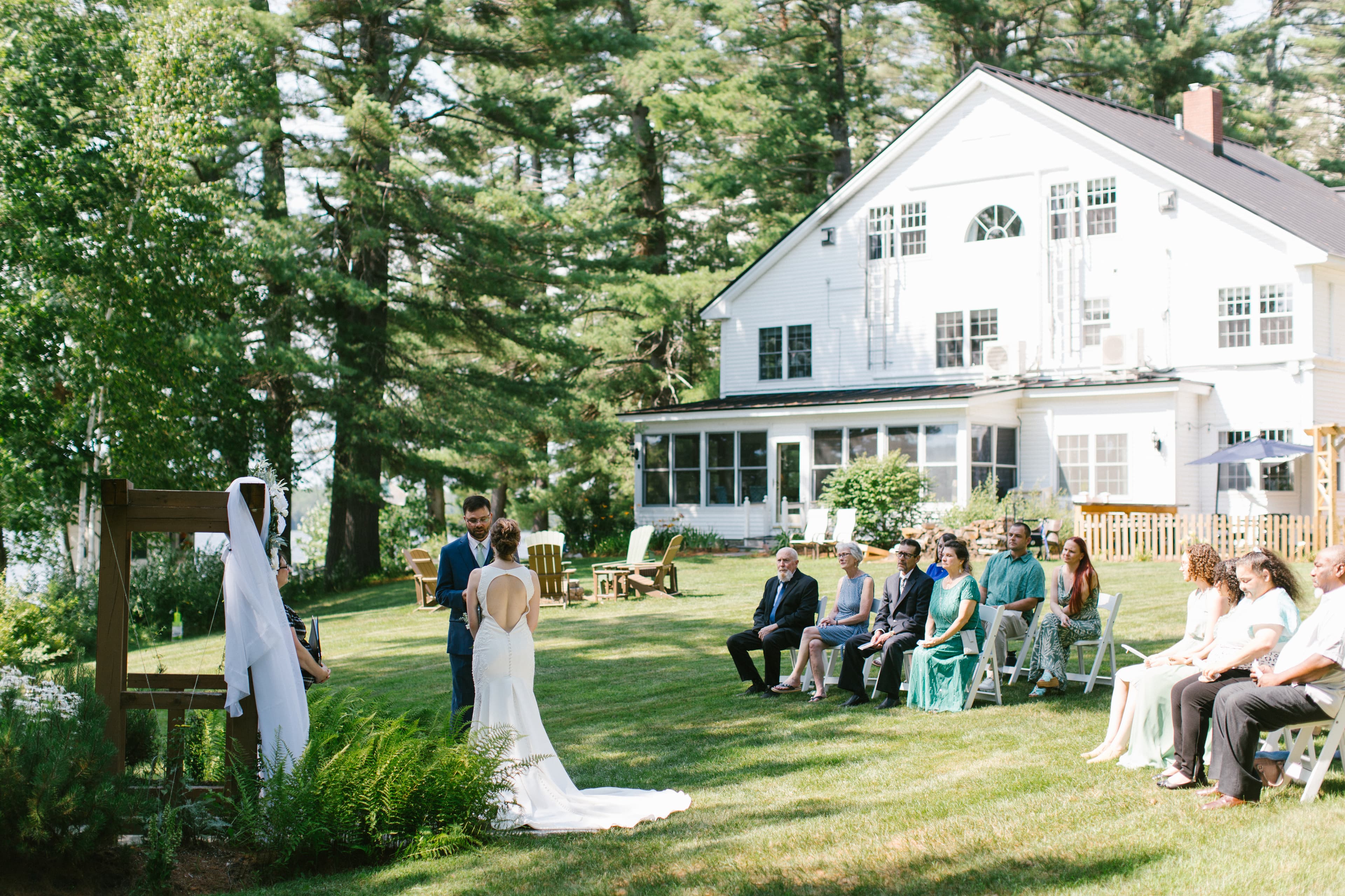 A couple exchanges vows during an outdoor wedding ceremony in a lush green setting.