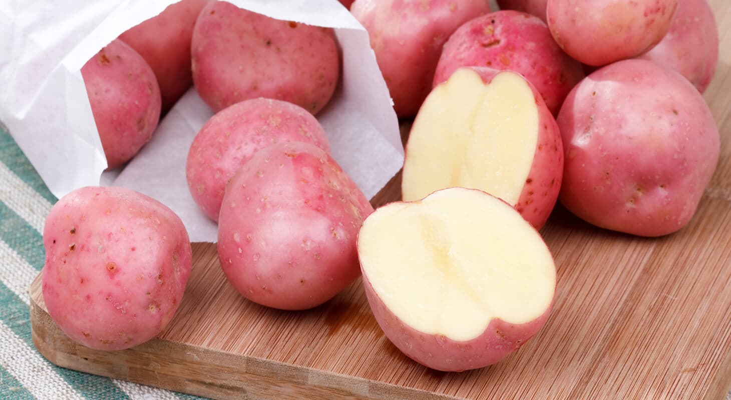 A pile of red potatoes, one cut in half to show its creamy interior. A pile of red potatoes, one cut in half to show its creamy interior.