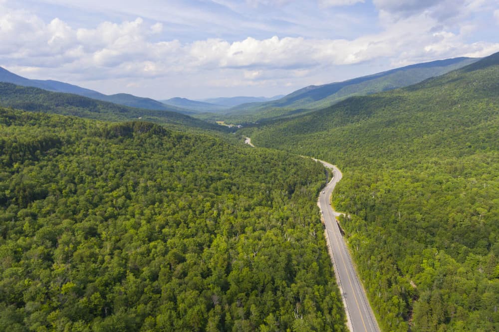 A winding road through a lush, green valley surrounded by mountains.