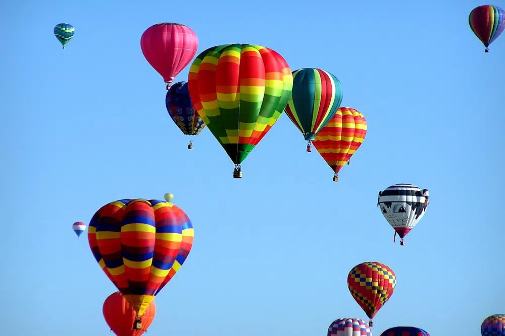 A vibrant array of colorful hot air balloons floating against a clear blue sky.