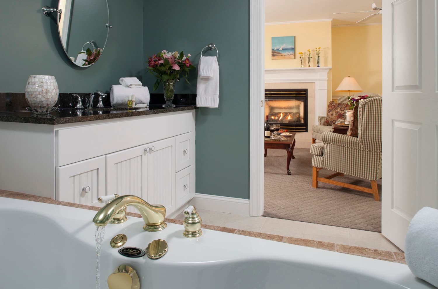 The sitting room chair and fireplace as seen from the bathroom (includes large granite vanity and 2 person spa tub).