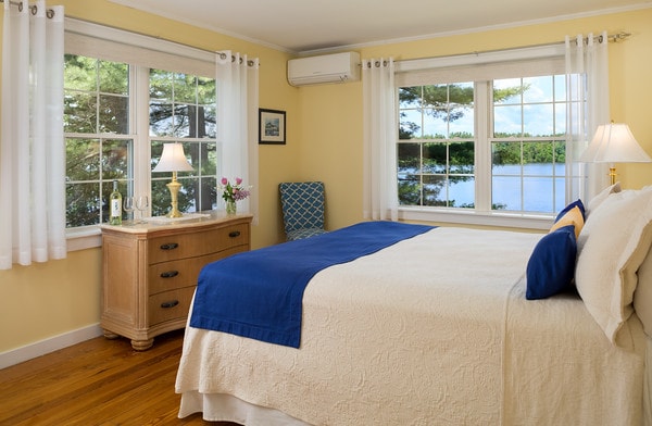The king bed, dresser, and corner windows which both overlook the lake.