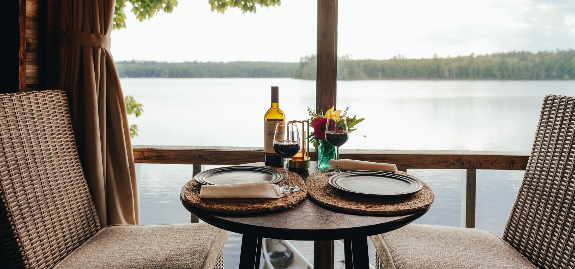 A cozy dining table set for two overlooks a serene lake.