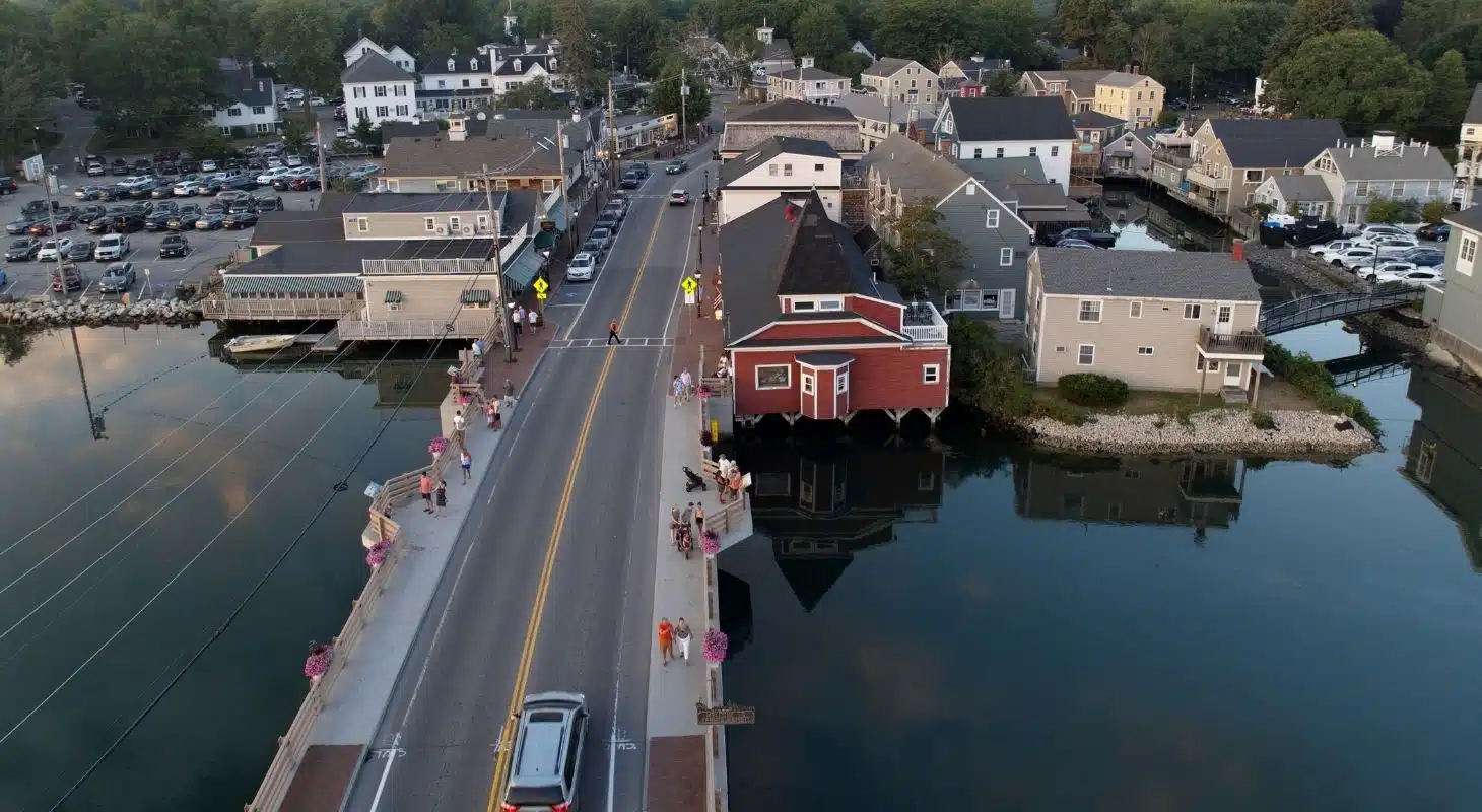 Aerial view of a bridge connecting a waterfront community with shops and homes alongside a calm waterway.