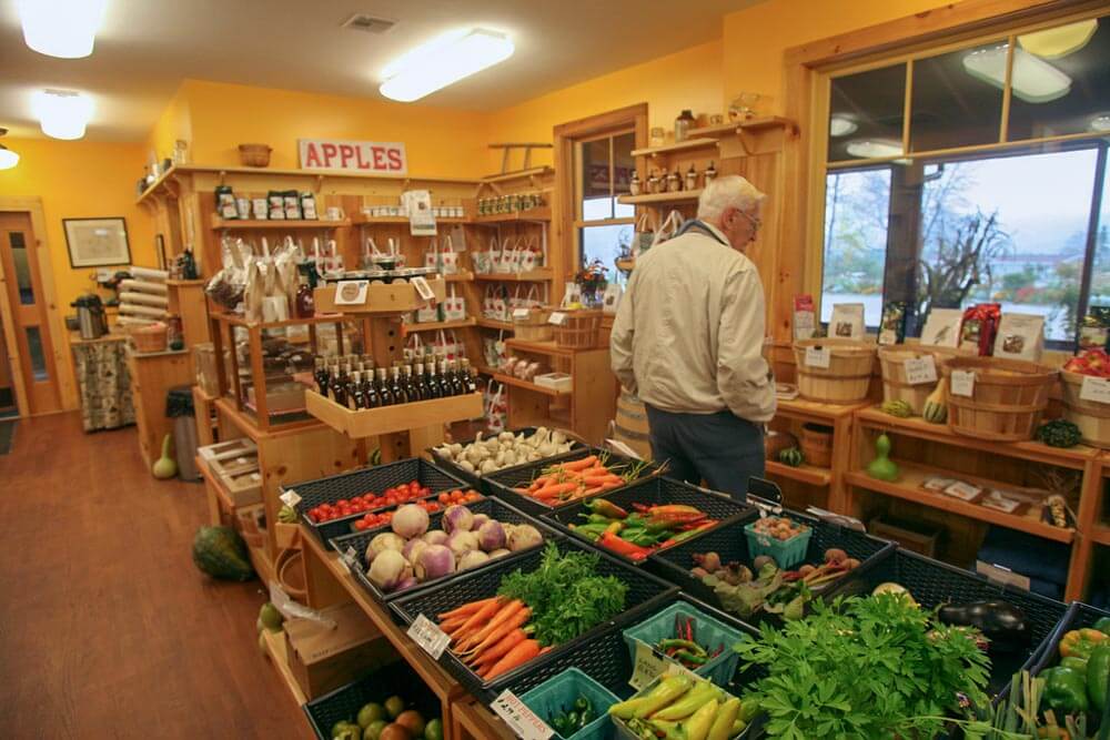 A customer browses through a vibrant display of fruits and vegetables in a cozy store.