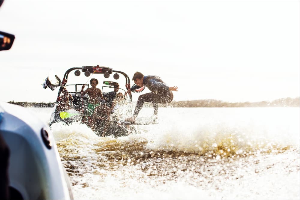 A person jumping off a boat while others enjoy the water in the background.