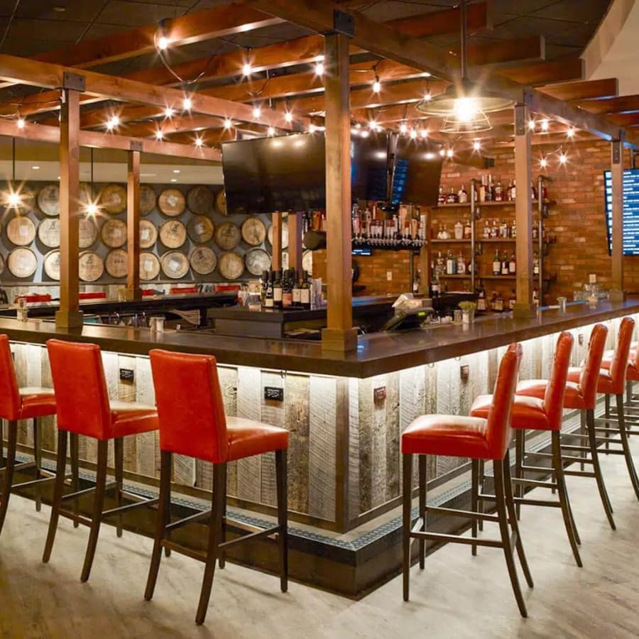 A stylish bar with illuminated seating and shelves stocked with various bottles.