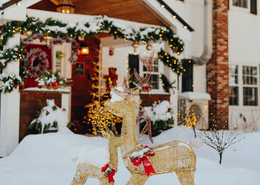 A decorated house in winter with snow, featuring lit reindeer decorations and festive greenery. A decorated house in winter with snow, featuring lit reindeer decorations and festive greenery.