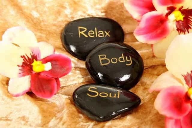 Three black stones engraved with "Relax," "Body," and "Soul," surrounded by pink orchids.