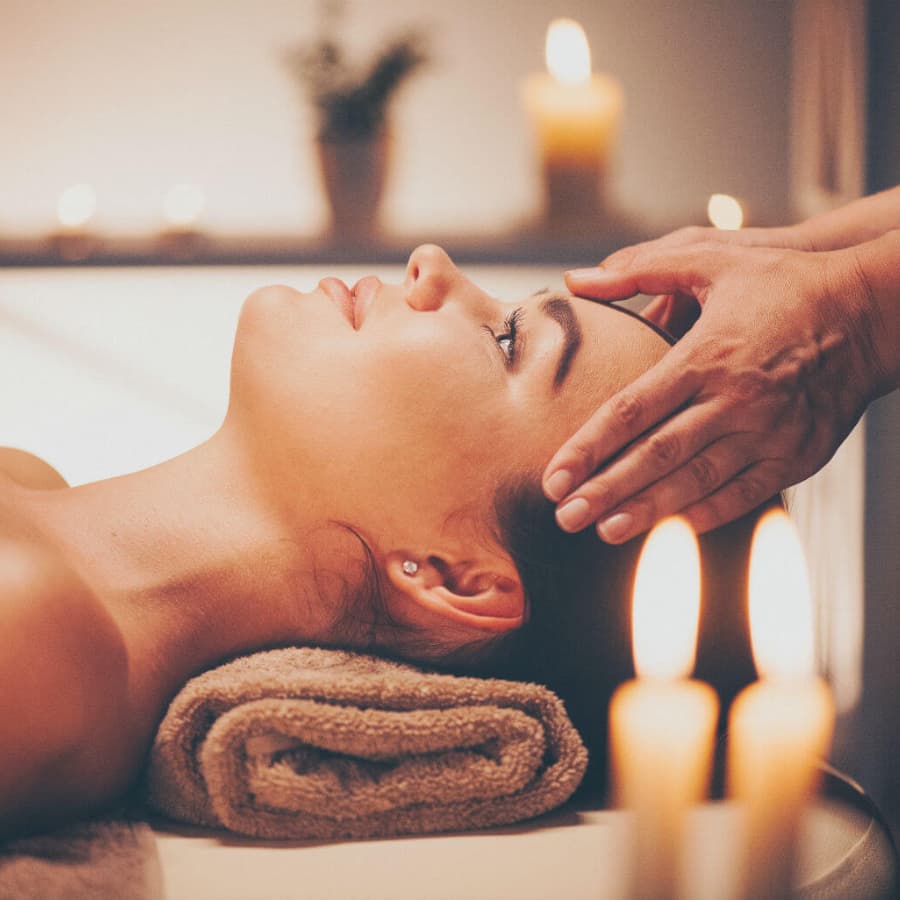 A woman receives a soothing head massage amid soft candlelight.