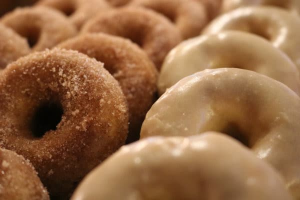 A close-up of freshly made donuts, featuring glazed and sugar-coated varieties.