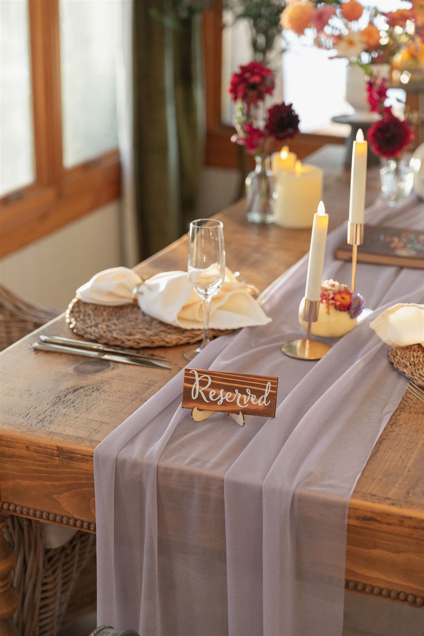 A beautifully set dining table with a "Reserved" sign, elegant glassware, and floral accents.