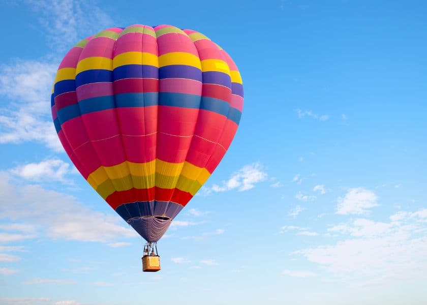 A colorful hot air balloon floats against a clear blue sky.