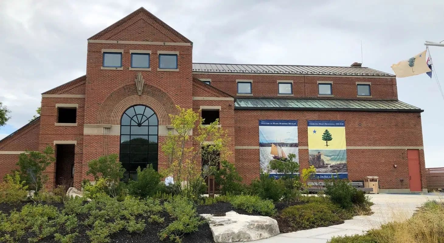 A brick building with large windows and banners, surrounded by landscaped greenery.