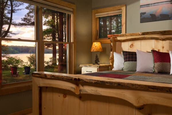 Custom made live pine edged king bed with window overlooking the pine grove and lake.