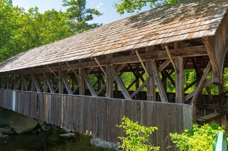 A rustic covered bridge surrounded by greenery.